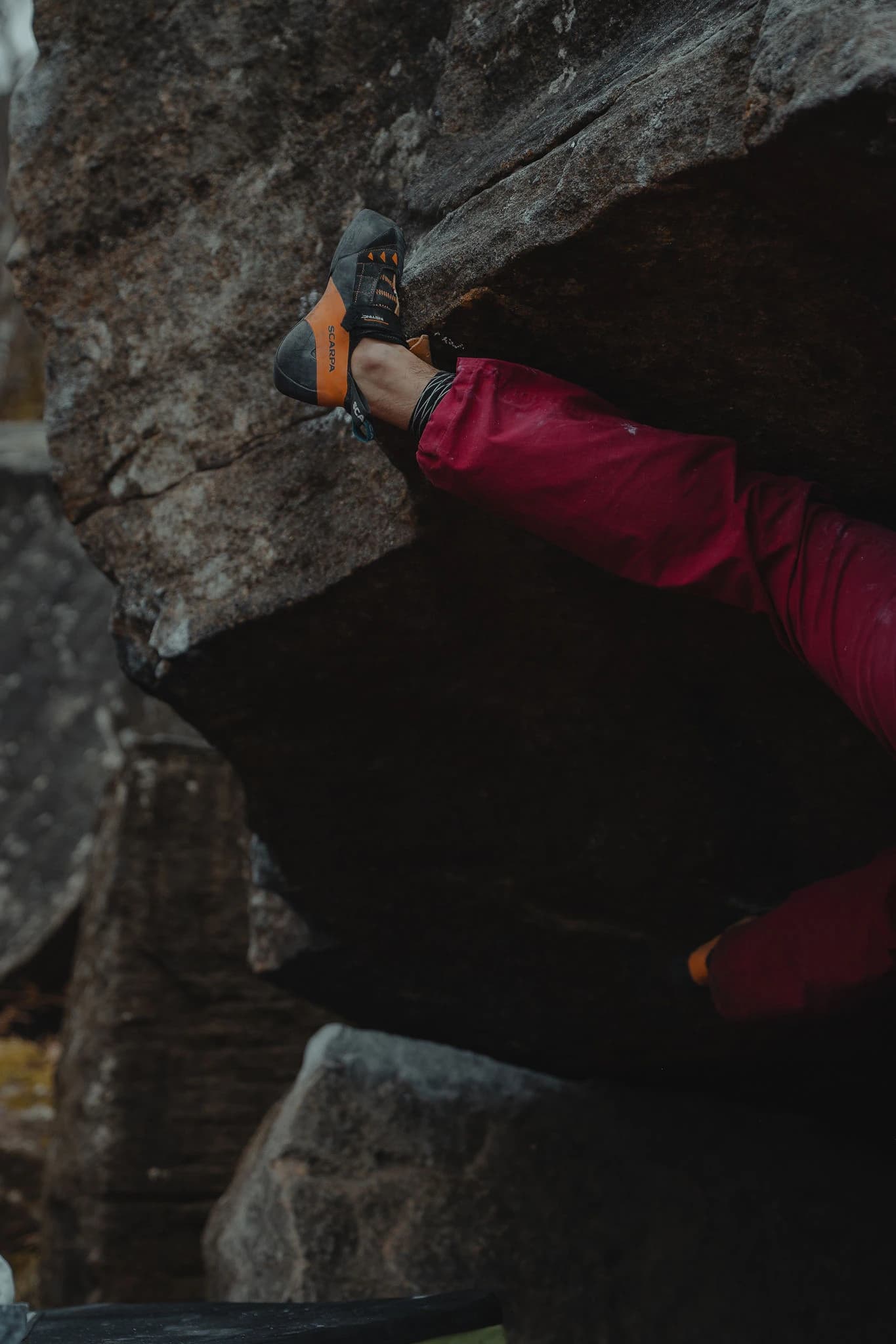 Climbing shoe wedged into a foothold on dark rock