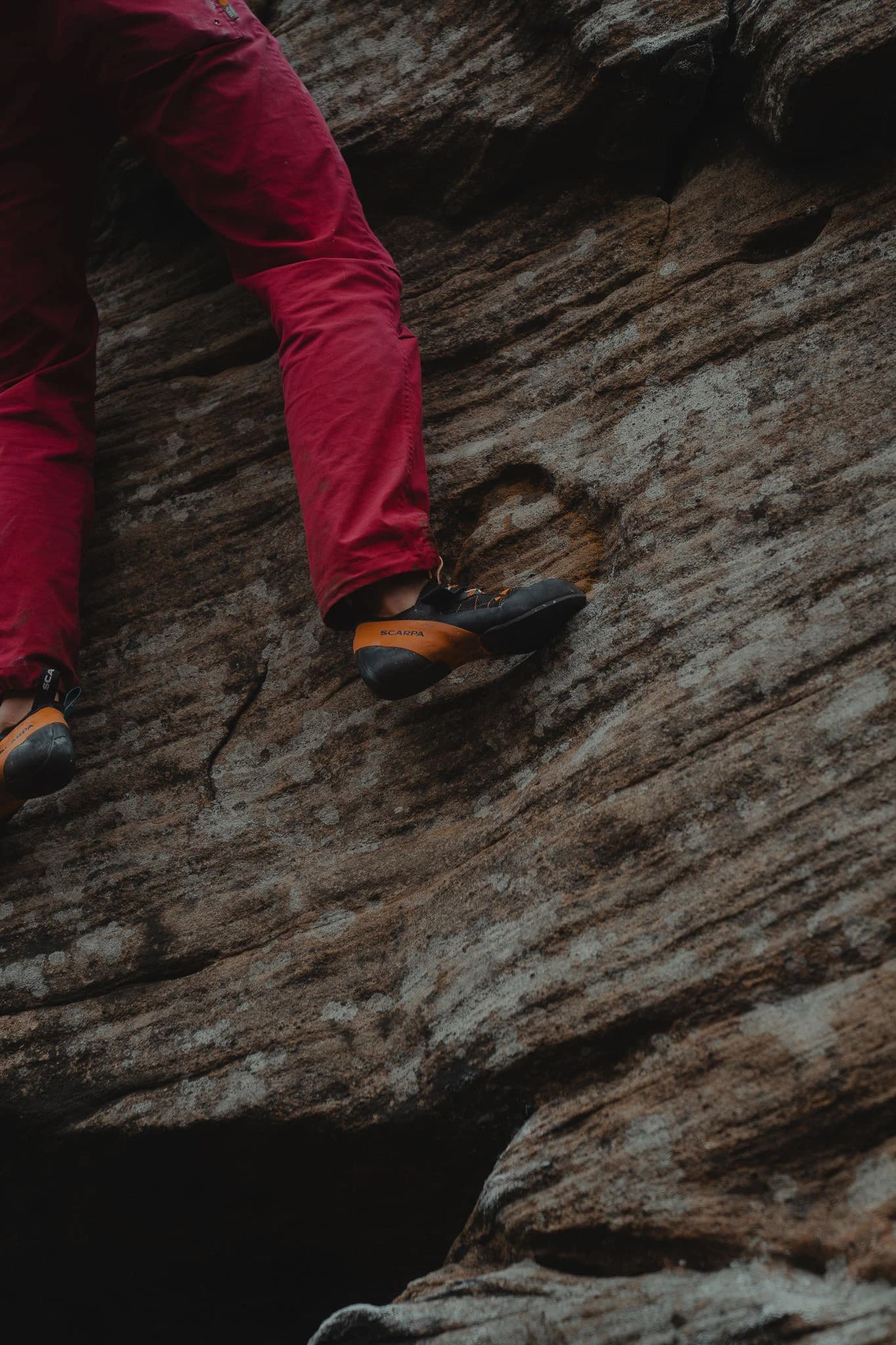 Close-up of climbing shoes on a textured rock ledge